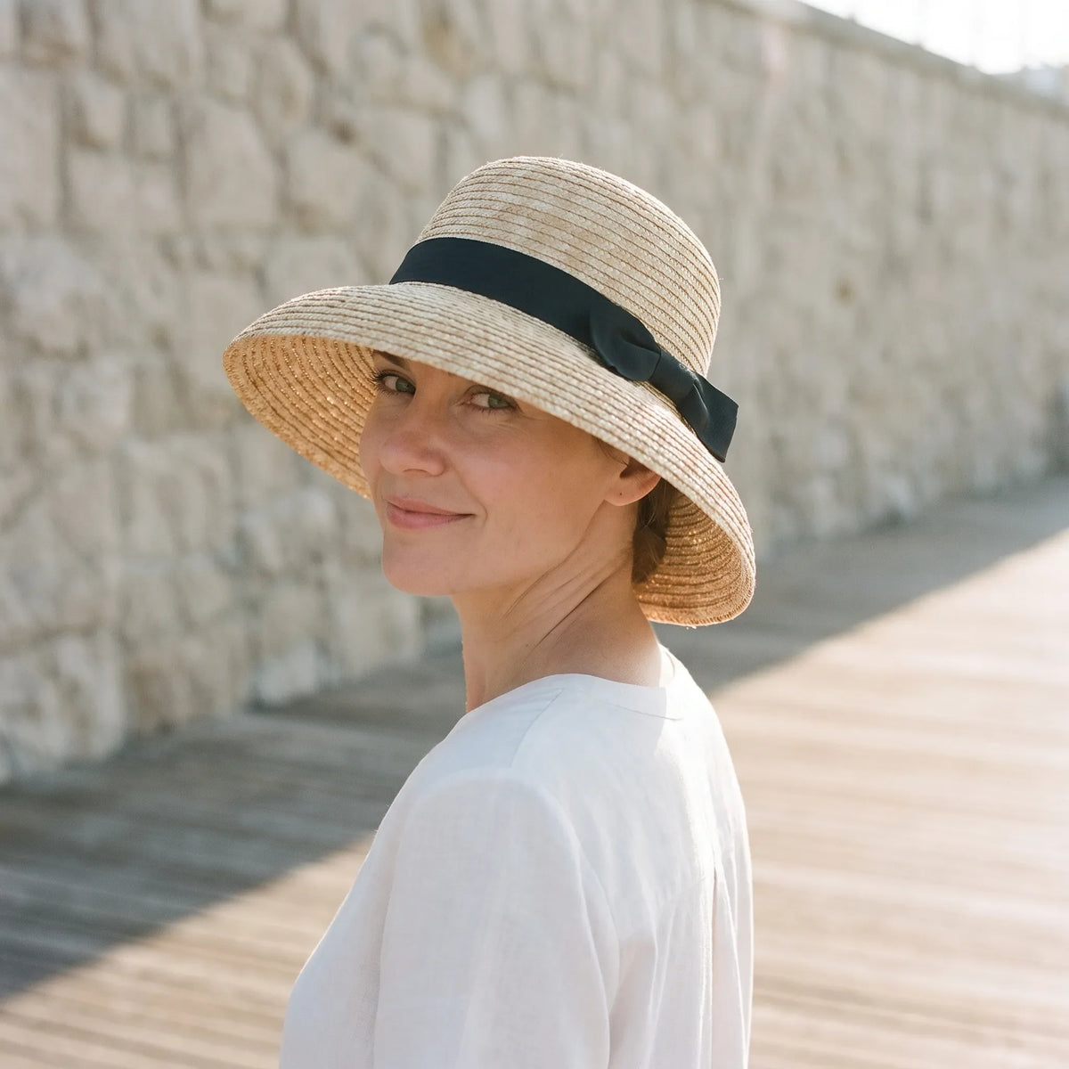 Woven cloche hat with wide brim and black ribbon bow detail