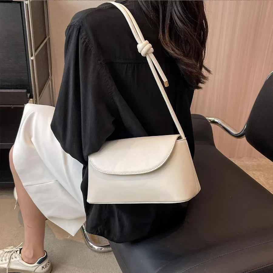 Compact square shoulder bag with knotted strap and flap closure