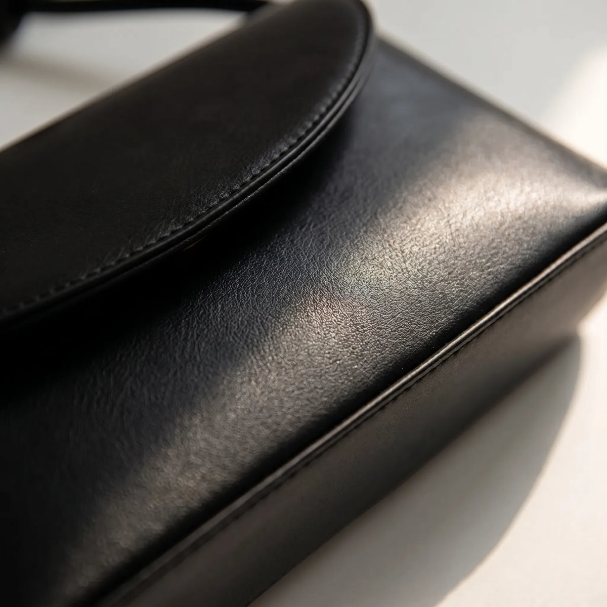 Compact square shoulder bag with knotted strap and flap closure